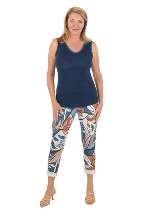 Woman wearing a navy sleeveless top and patterned pants on a white background.