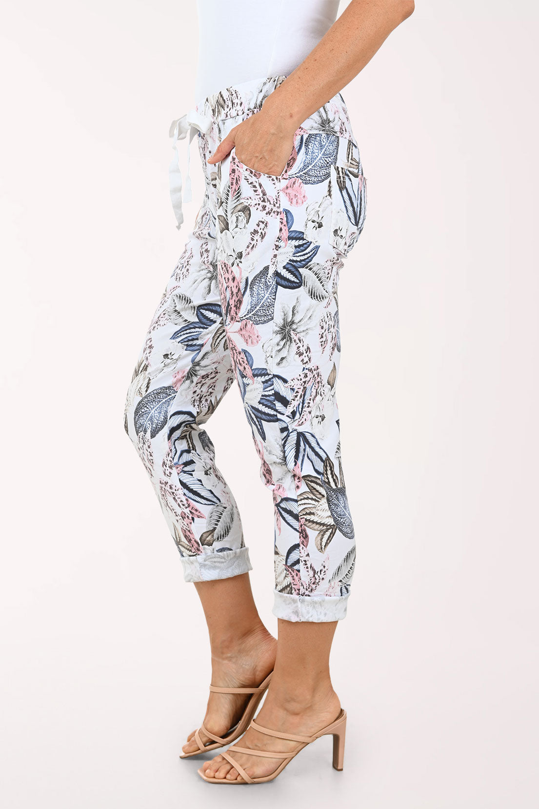 Woman wearing a pink blouse and floral pants on a white background