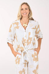 Woman wearing a white blouse with beige floral patterns on a light pink background
