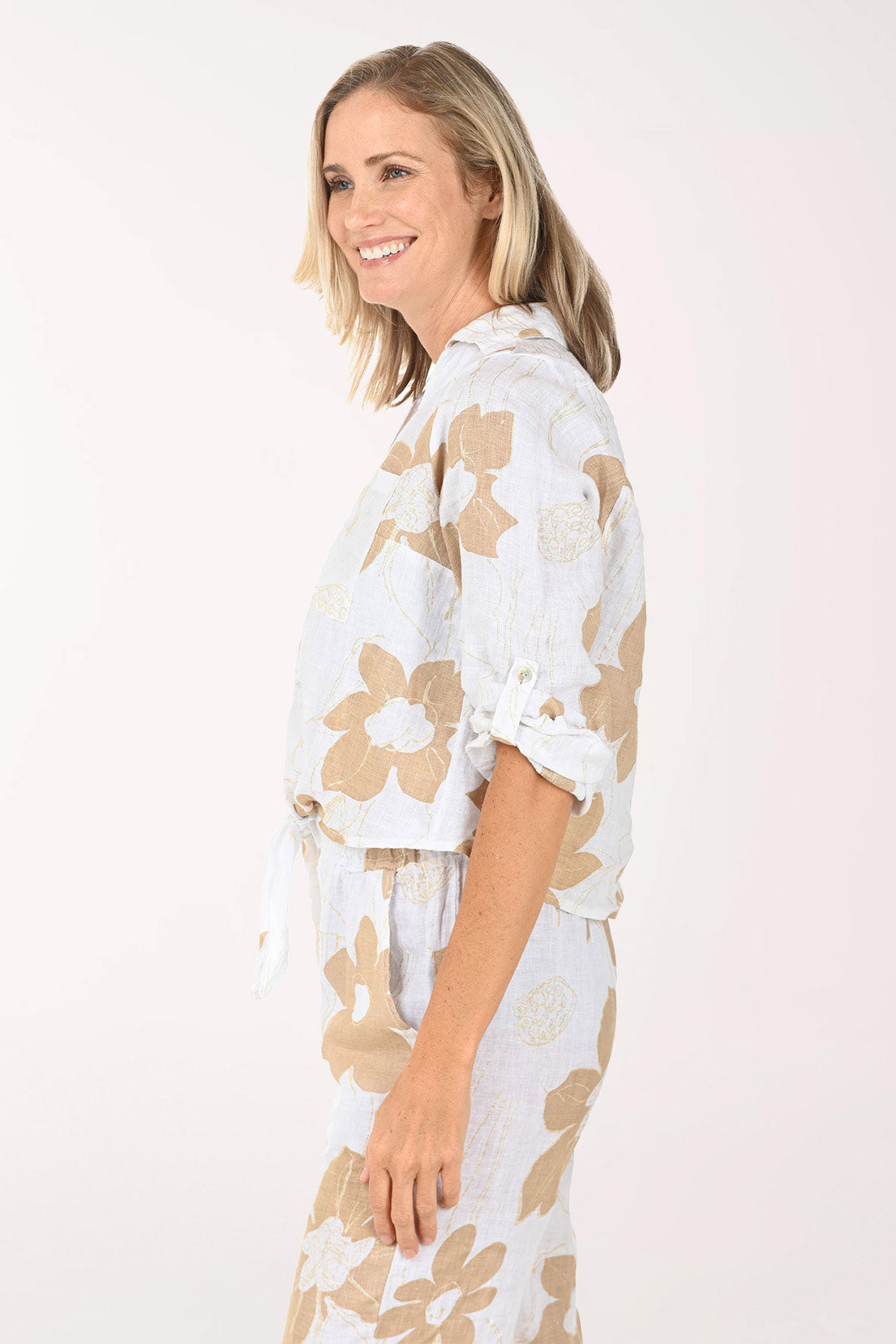 Woman wearing a white blouse with beige floral patterns on a light pink background