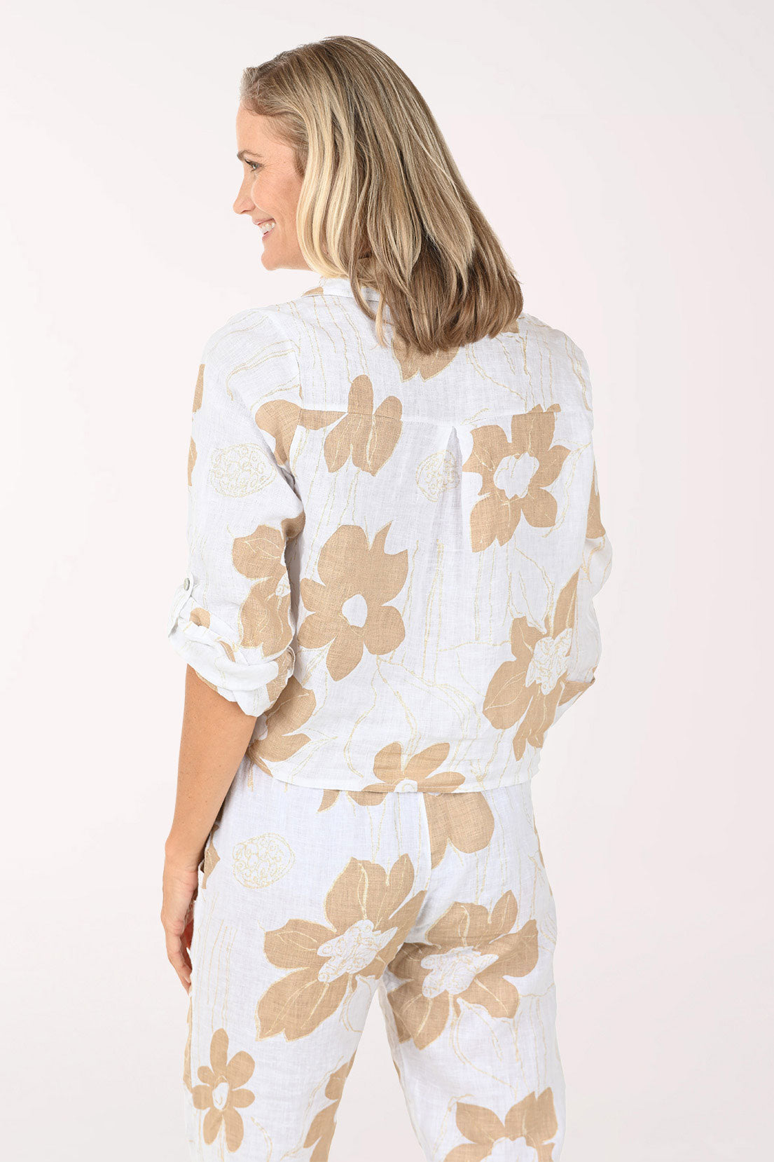 Woman wearing a white blouse with beige floral patterns on a light pink background