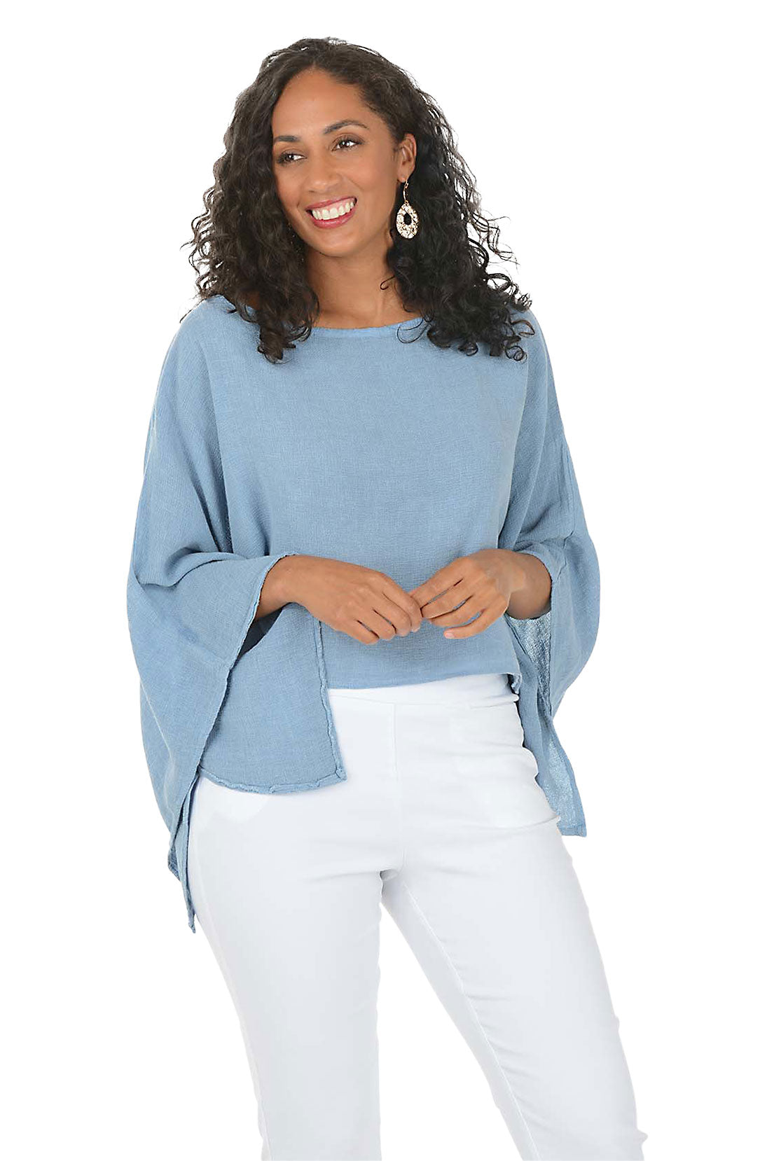 Woman wearing a blue sweater and white pants on a white background.