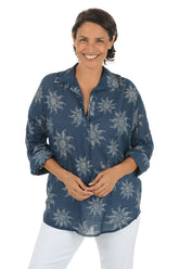 Woman wearing a blue floral patterned shirt on a white background.