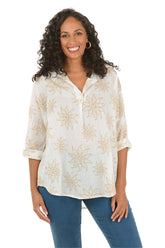 Woman wearing a white blouse with floral patterns and blue jeans on a white background.
