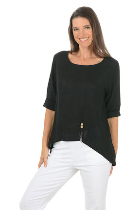 Woman wearing a black top and white pants on a white background.