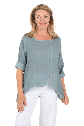 Woman wearing a light blue top and white pants on a white background.