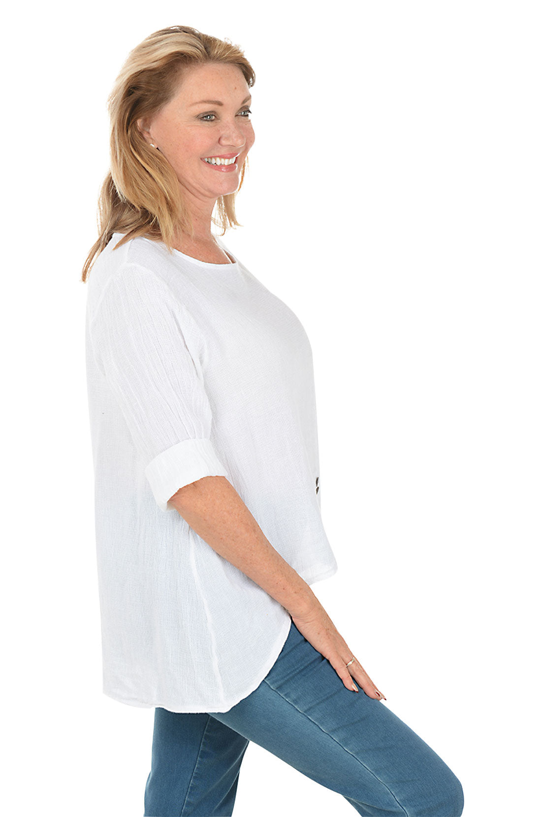Woman wearing a white blouse and blue jeans on a white background. Side shot.