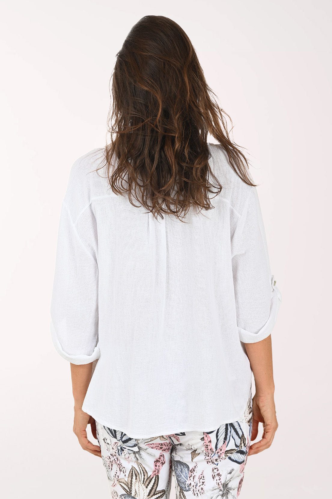 Woman wearing a white shirt and floral pants on a white background