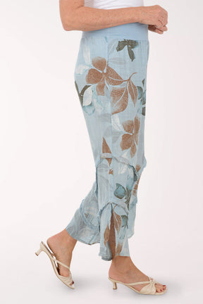 Woman wearing blue flowy pants with printed flowers.