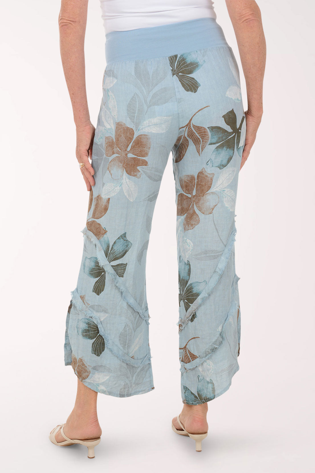 Woman wearing blue flowy pants with printed flowers.