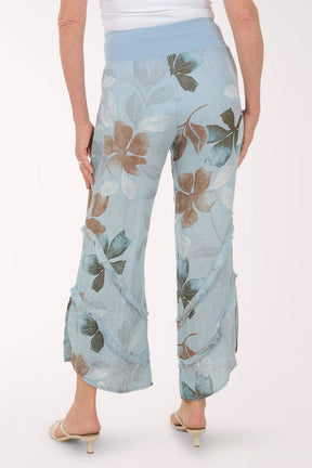 Woman wearing blue flowy pants with printed flowers.
