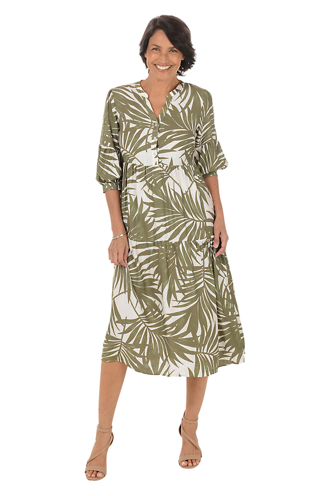Woman wearing a green and white leaf-patterned dress on a white background.