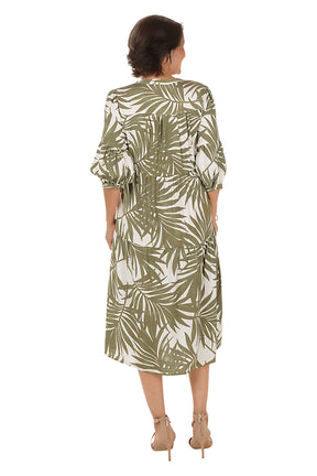 Woman wearing a green and white leaf-patterned dress on a white background. Back shot.