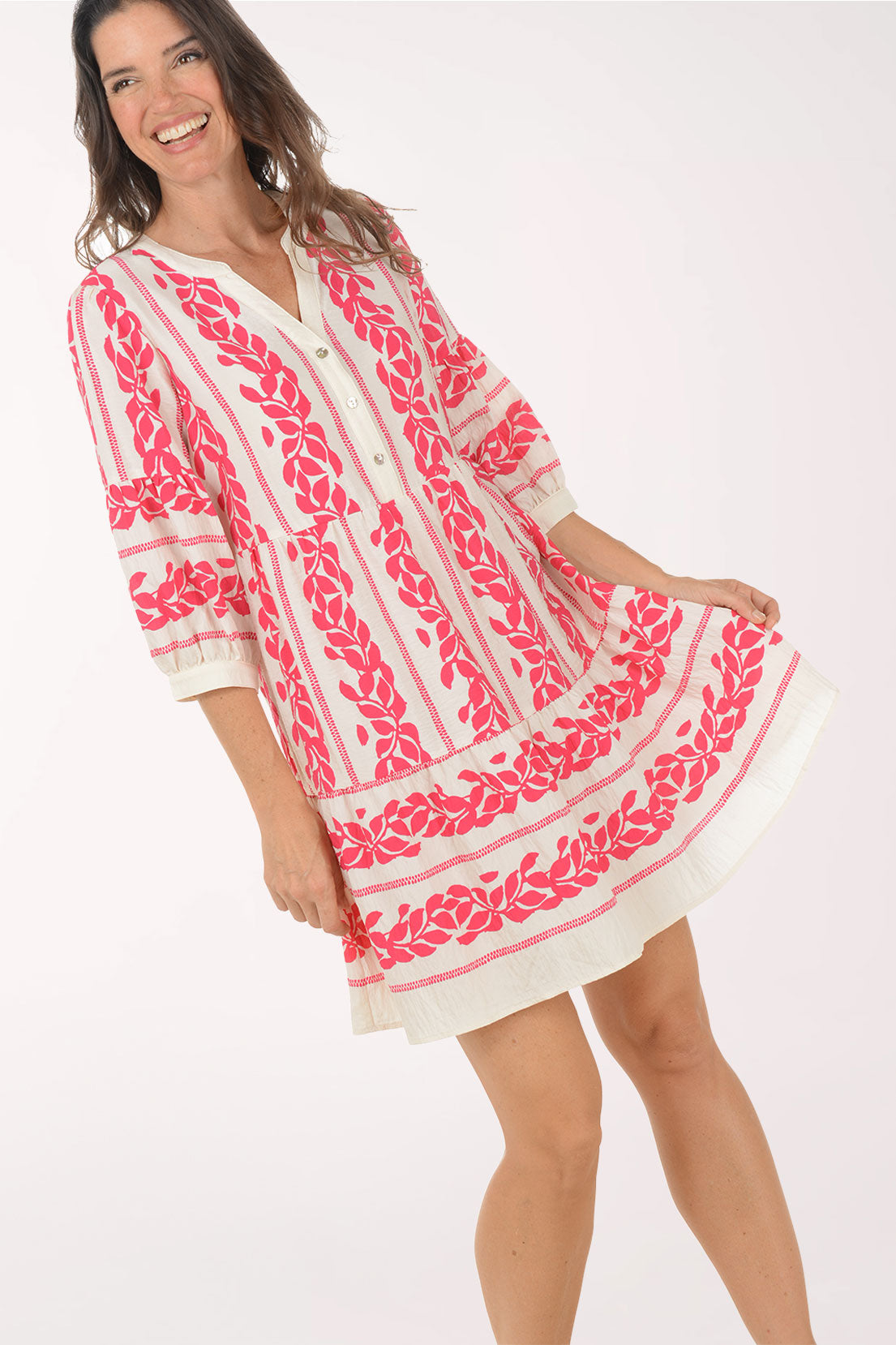 Woman wearing a pink and white embroidered dress on a white background