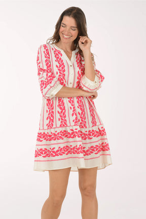 Woman wearing a pink and white embroidered dress on a white background
