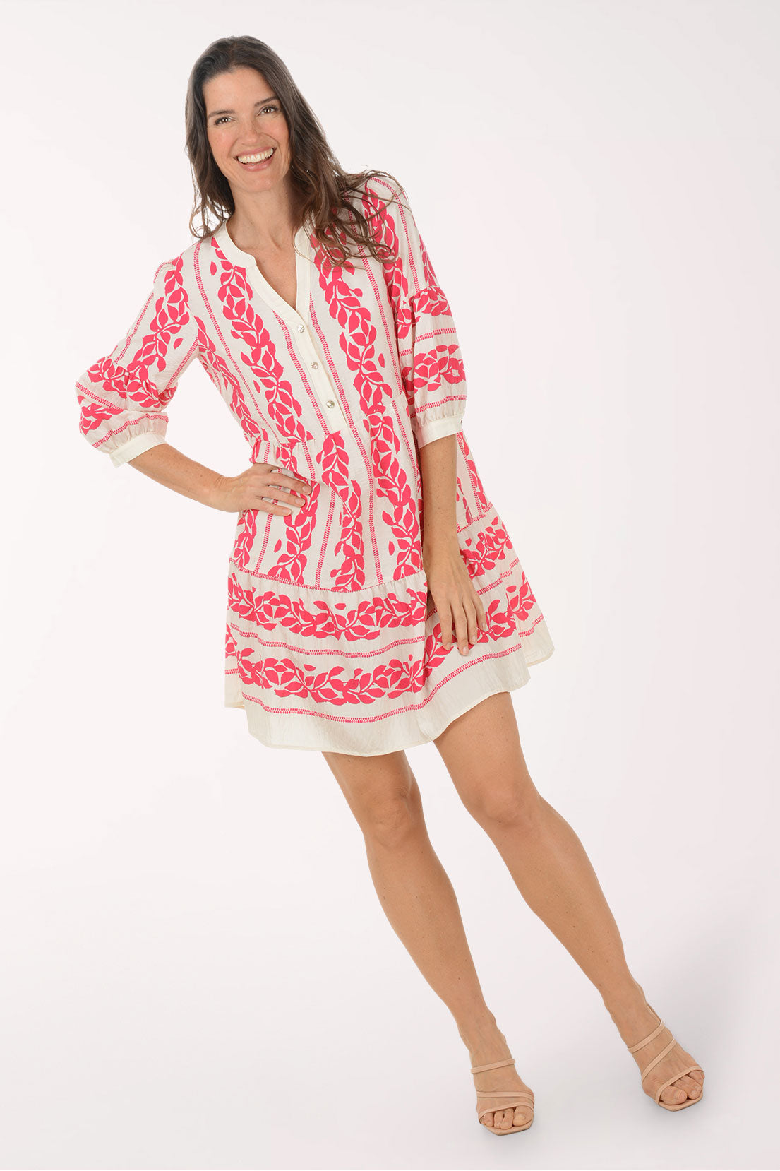 Woman wearing a pink and white embroidered dress on a white background