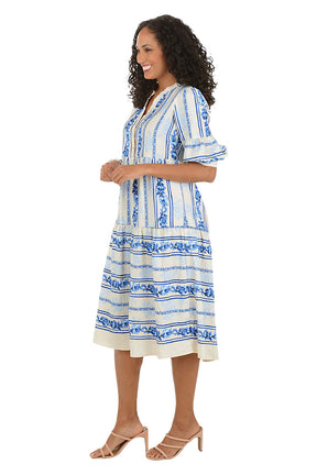 Woman wearing a blue and white patterned midi dress on a white background. Side shot.