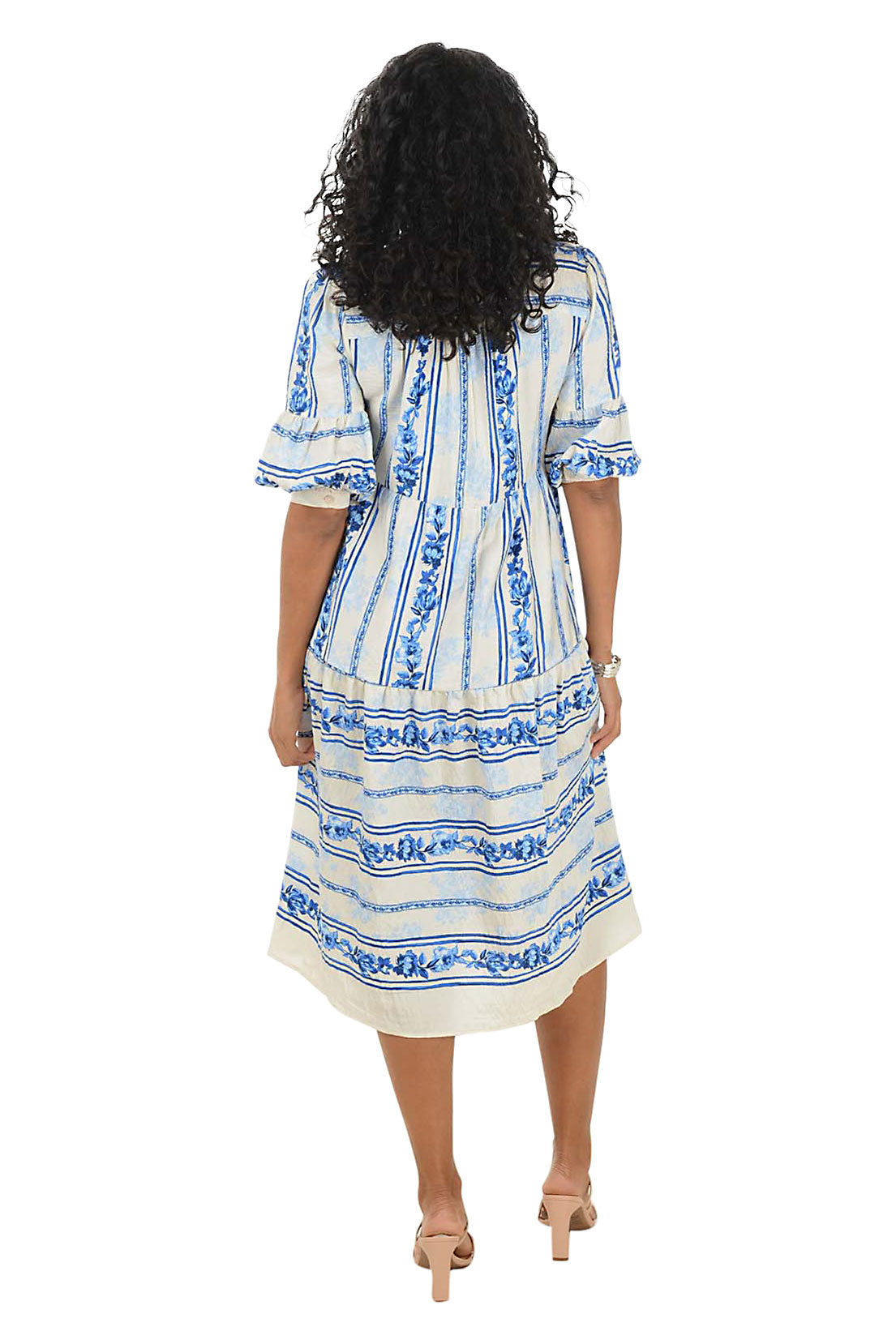 Woman wearing a blue and white patterned midi dress on a white background. Back shot.