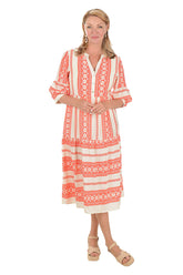 Woman wearing a coral and white patterned midi dress on a white background.