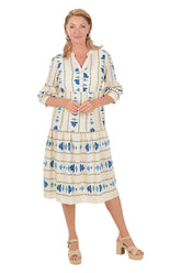 Woman wearing a white midi dress with blue floral patterns on a white background.