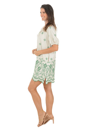 Woman wearing a green and white patterned dress on a white background. Side shot.