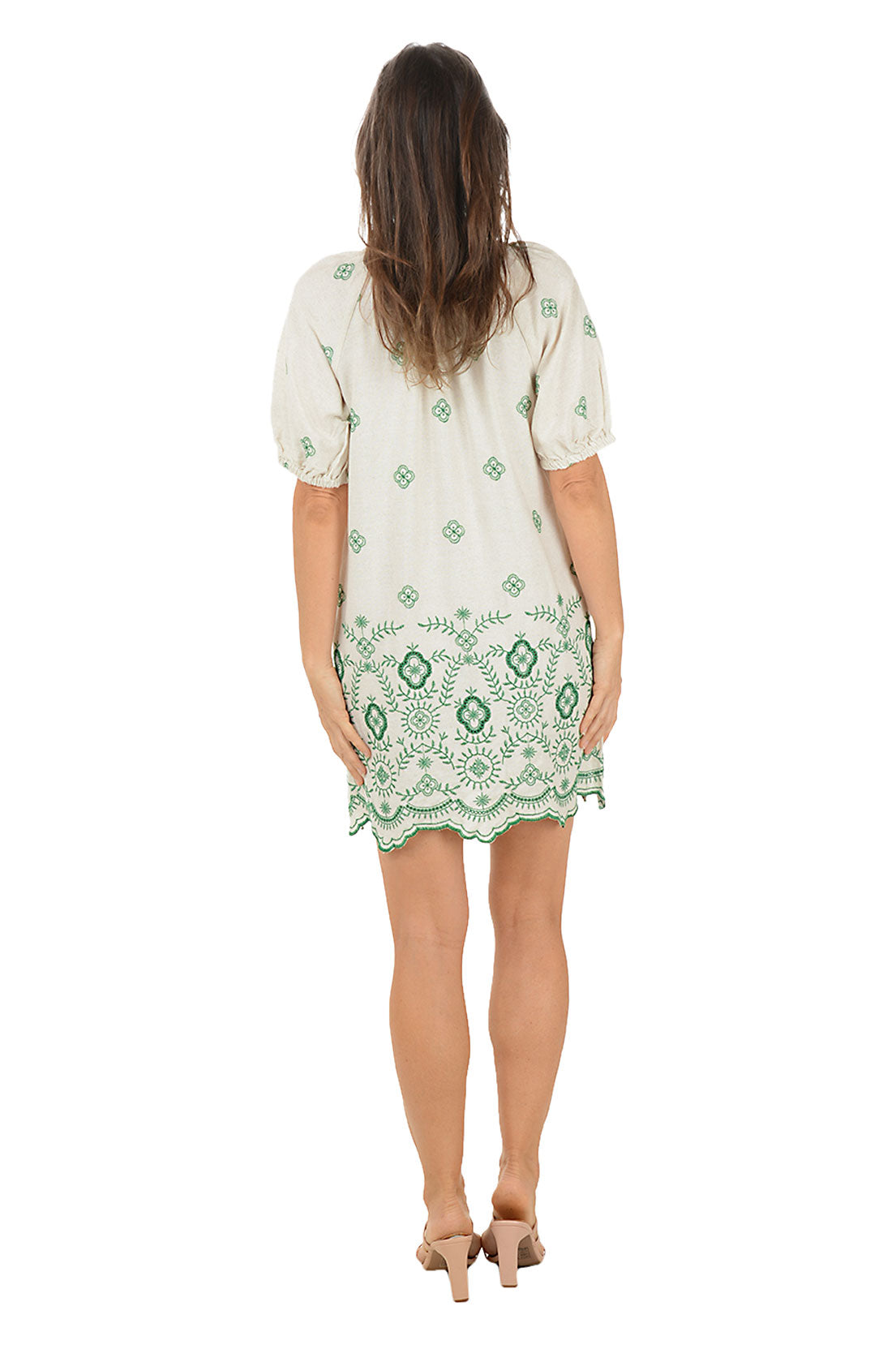 Woman wearing a green and white patterned dress on a white background. Back shot.
