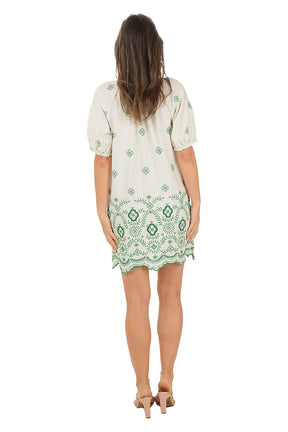 Woman wearing a green and white patterned dress on a white background. Back shot.