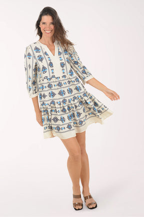 Woman wearing a white dress with blue floral patterns on a white background