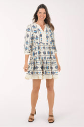 Woman wearing a white dress with blue floral patterns on a white background