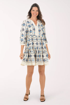 Woman wearing a white dress with blue floral patterns on a white background