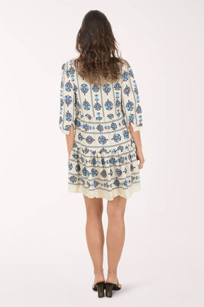 Woman wearing a white dress with blue floral patterns on a white background