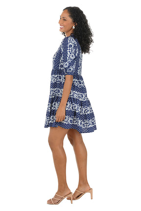 Woman wearing a blue patterned dress on a white background. Side shot.