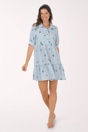 Woman wearing a light blue dress with floral pattern on a white background