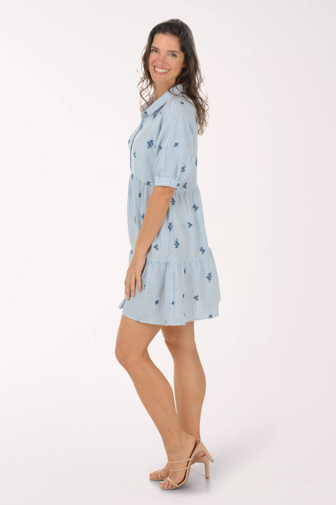 Woman wearing a light blue dress with floral pattern on a white background