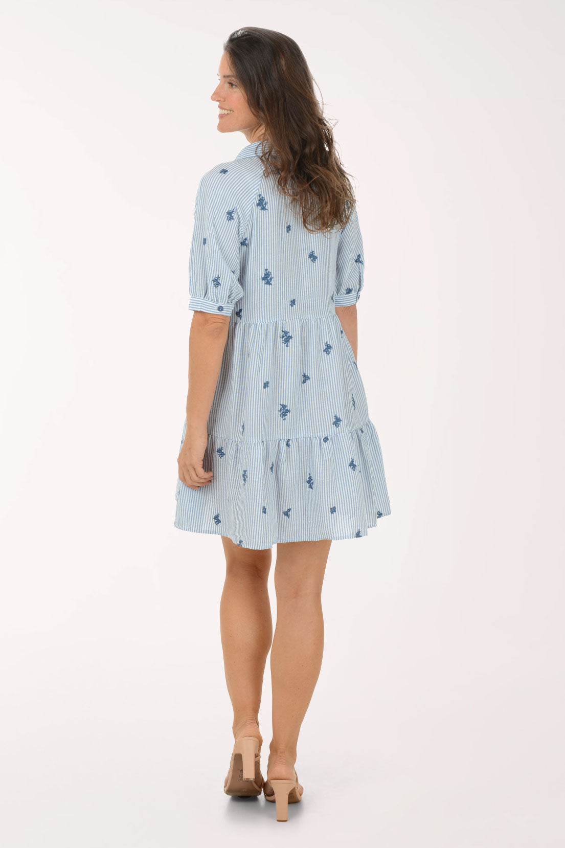 Woman wearing a light blue dress with floral pattern on a white background