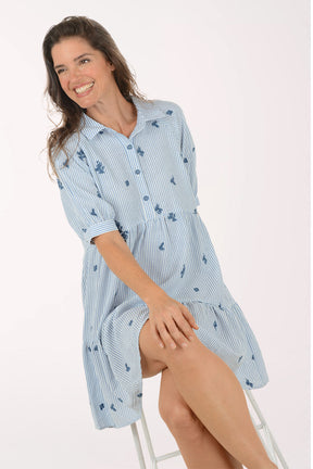 Woman wearing a light blue dress with floral pattern on a white background