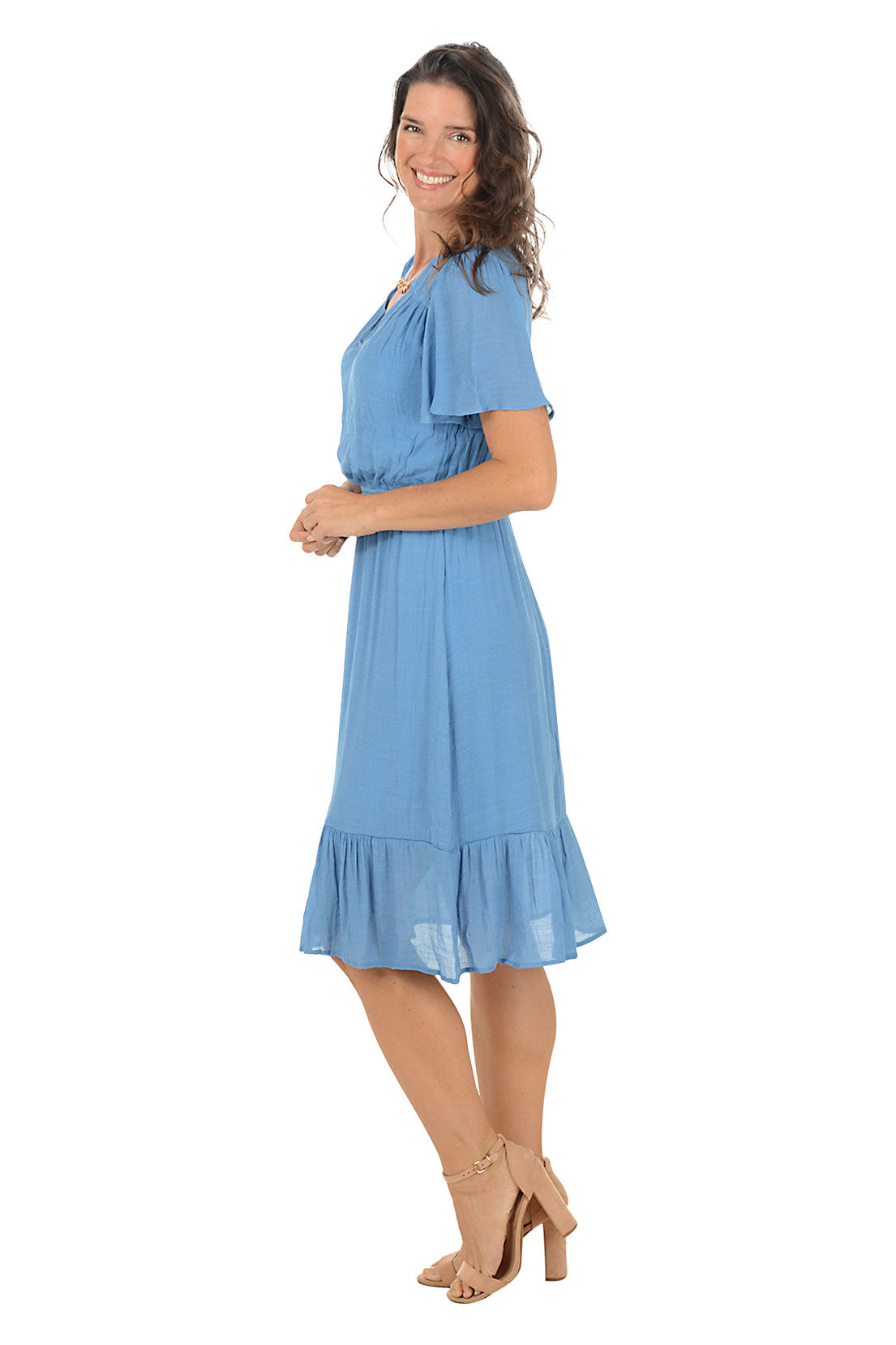 Woman wearing a blue dress on a white background. Side shot.