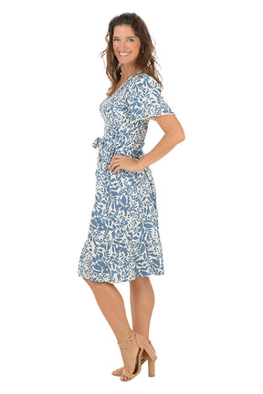 Woman wearing a blue floral dress on a white background. Side shot.