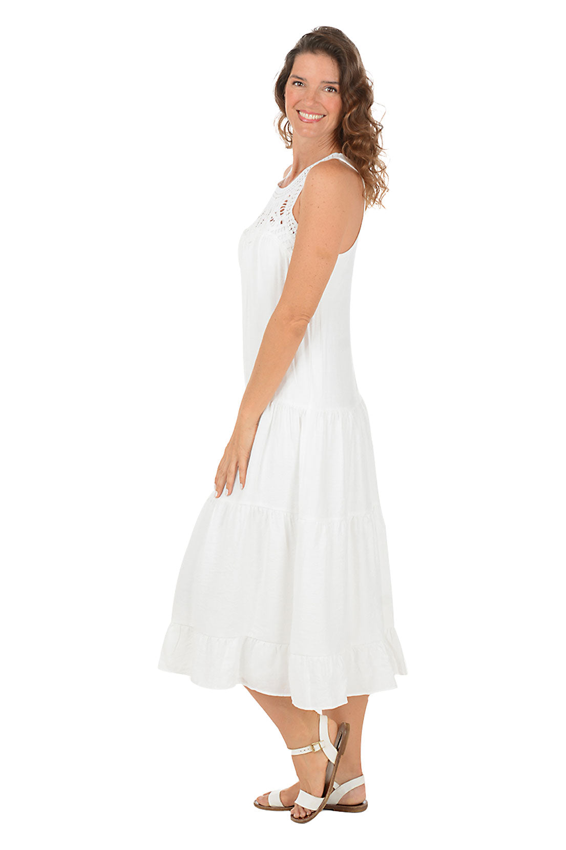 A woman wearing a white halter midi dress with a crochet neckline.  Side shot.