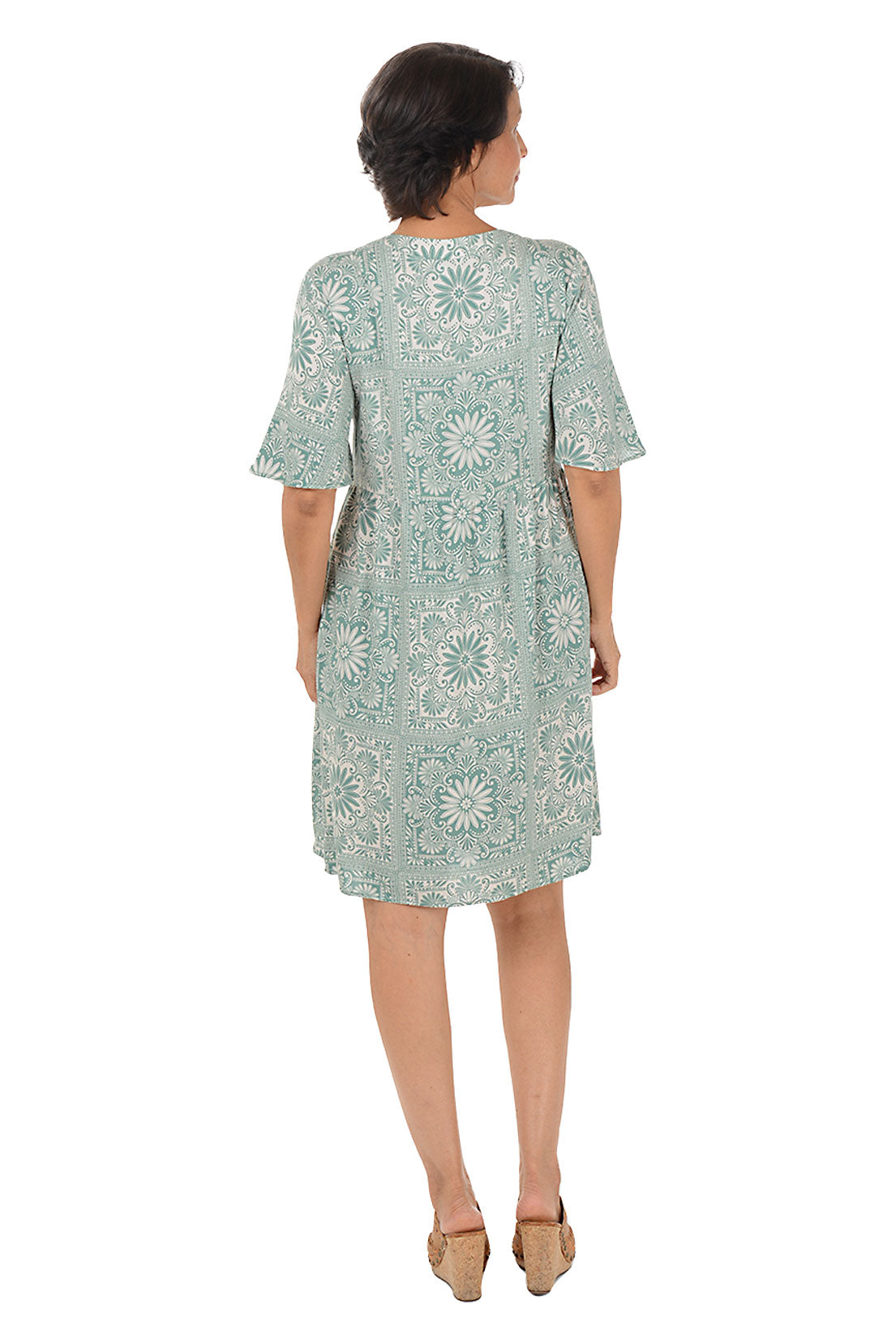 Woman wearing a patterned dress on a white background. Back shot.
