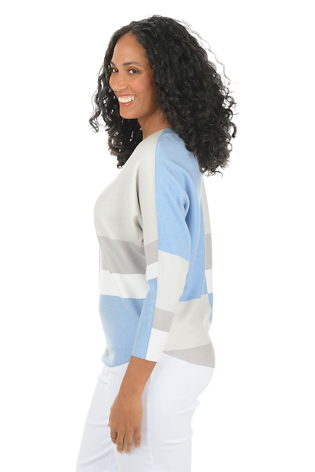 Woman wearing a blue and grey geometric block sweater with dolman sleeves on a white background. Side shot.