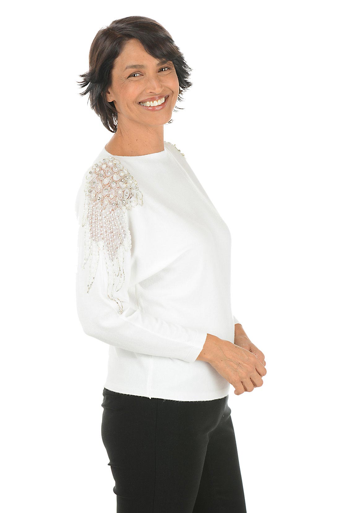 Woman wearing a white long sleeve sweater with sheer mesh angel wing embellishments with beaded and rhinestone accents on shoulders. Side shot.