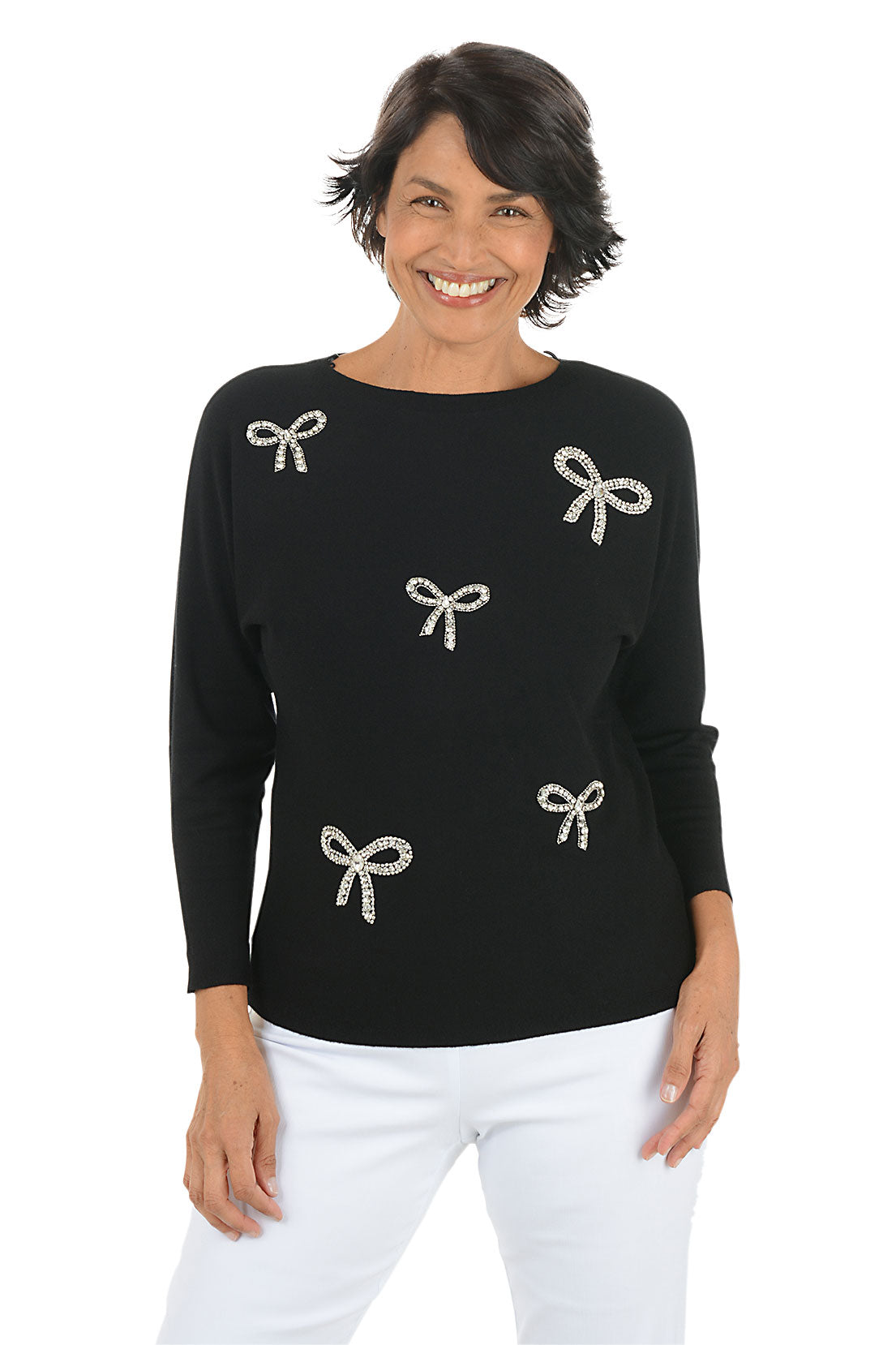 Woman wearing a black long sleeve sweater with rhinestone bow embellishments. 