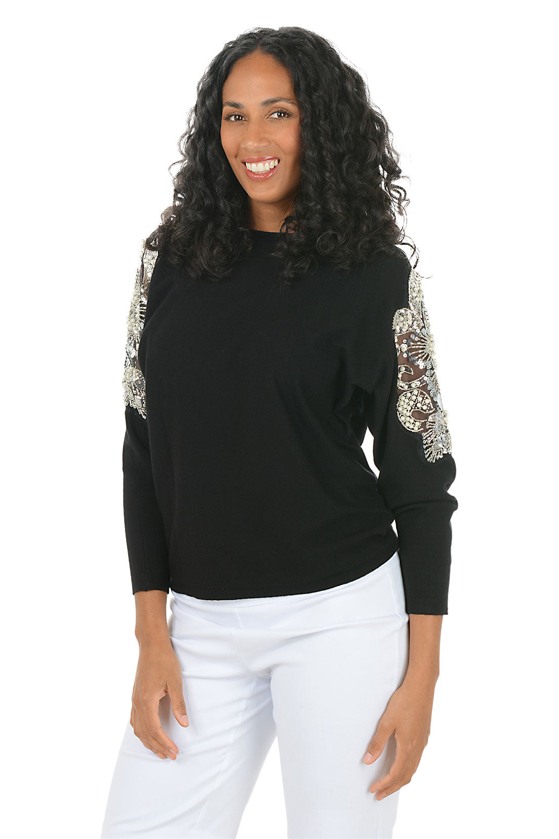 Woman wearing a long sleeve black sweater with floral embellished appliques on the arm.