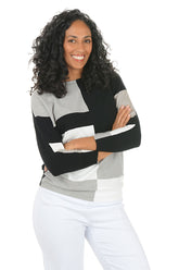 Woman wearing a black, gray, and white striped sweater with arms crossed on a white background.