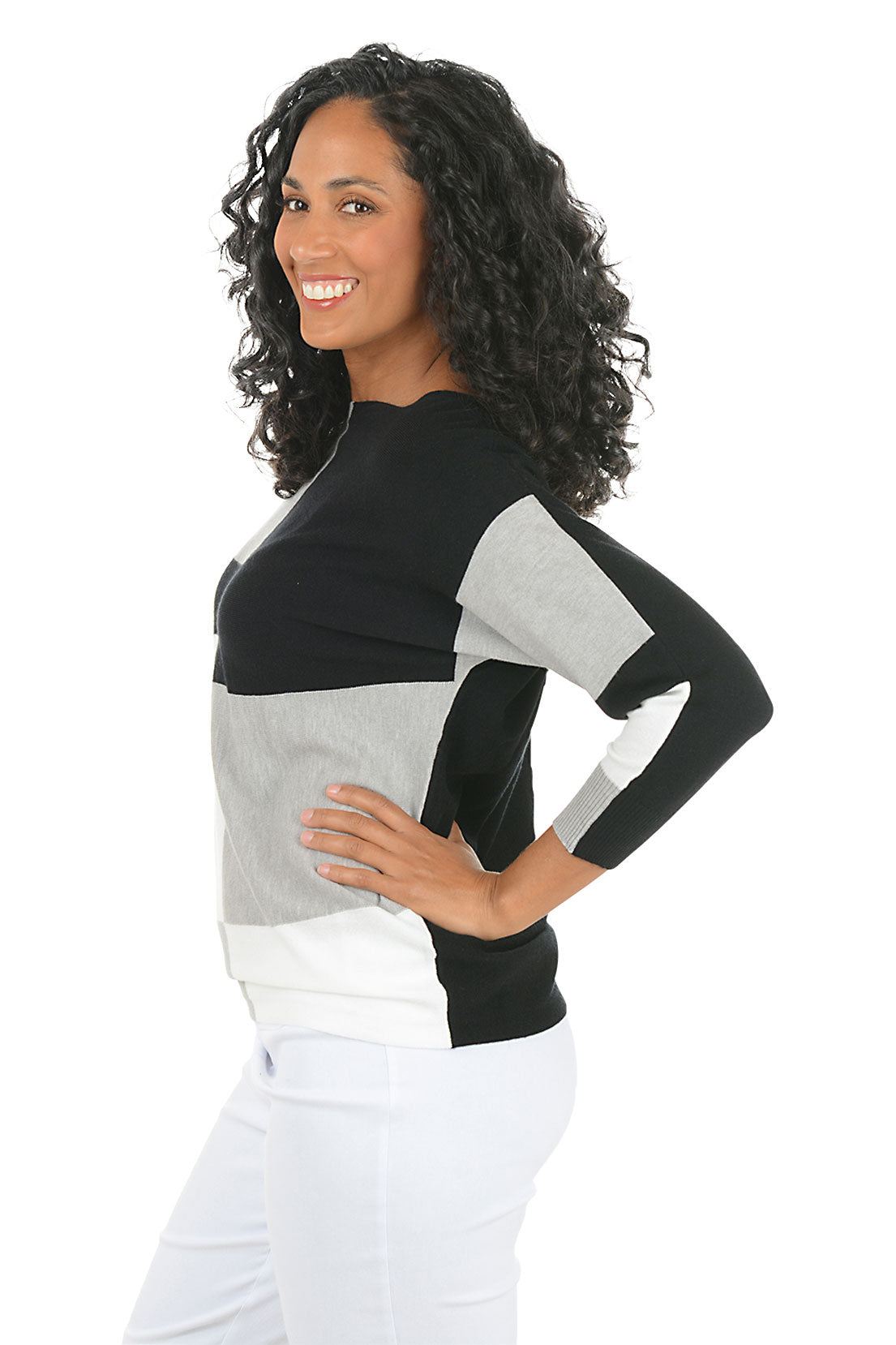 Woman wearing a black, gray, and white color-blocked sweater on a white background. Side shot.