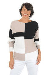 Woman wearing a color-blocked sweater with beige, black, and white design on a white background.