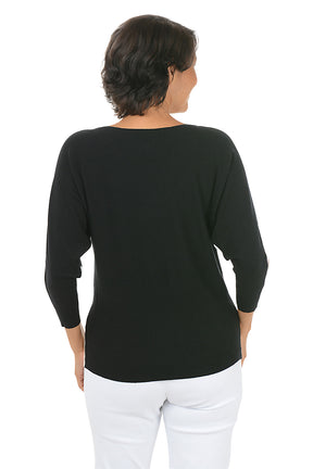Woman wearing a color-blocked sweater with beige, black, and white design on a white background. Back shot.