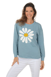 Woman wearing a blue sweatshirt with a white daisy design on a white background.