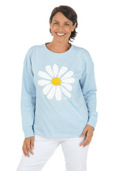 Woman wearing a light blue sweatshirt with a white daisy design on a white background